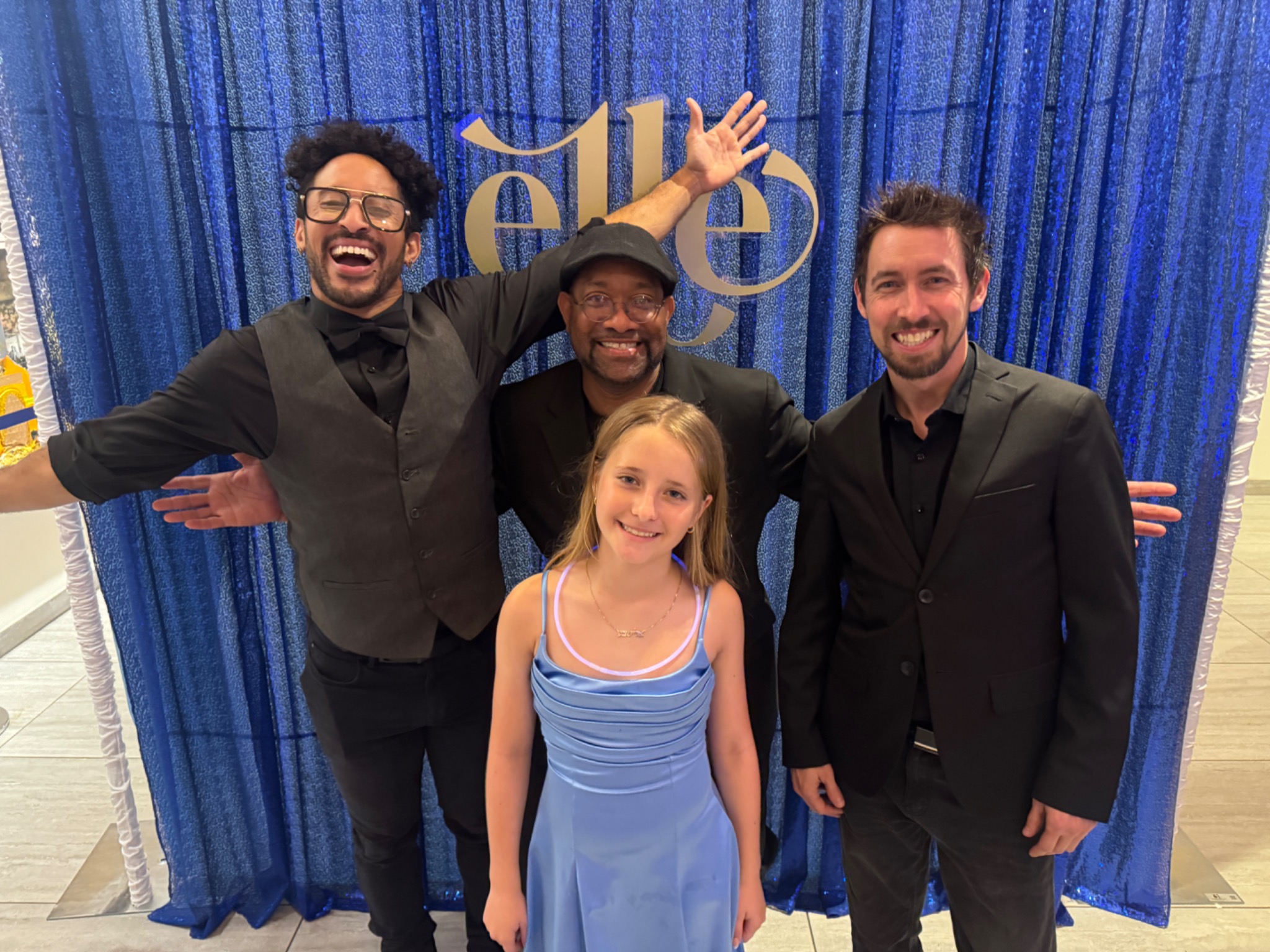A group posing in front of a blue celebration backdrop